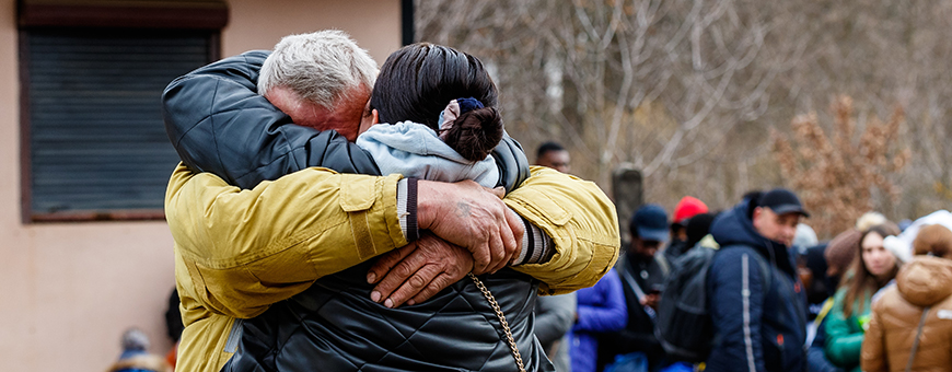 Uzhhorod, Ukraine - February 26, 2022: A man on the background of Ukrainian refugees says goodbye to his wife who is fleeing Russian aggression. Refugees on the Ukrainian-Slovak border.